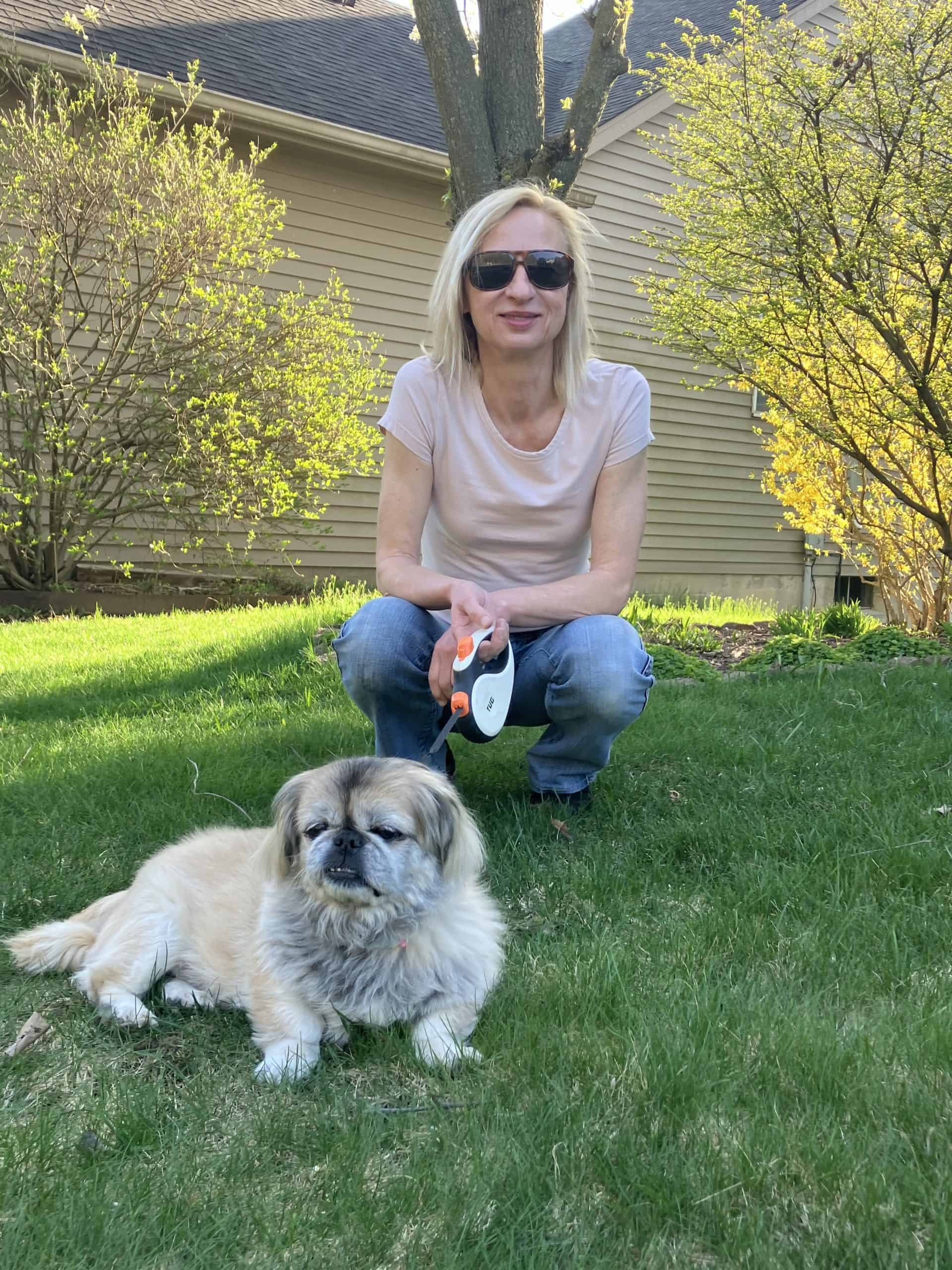 woman crouching down next to a small dog